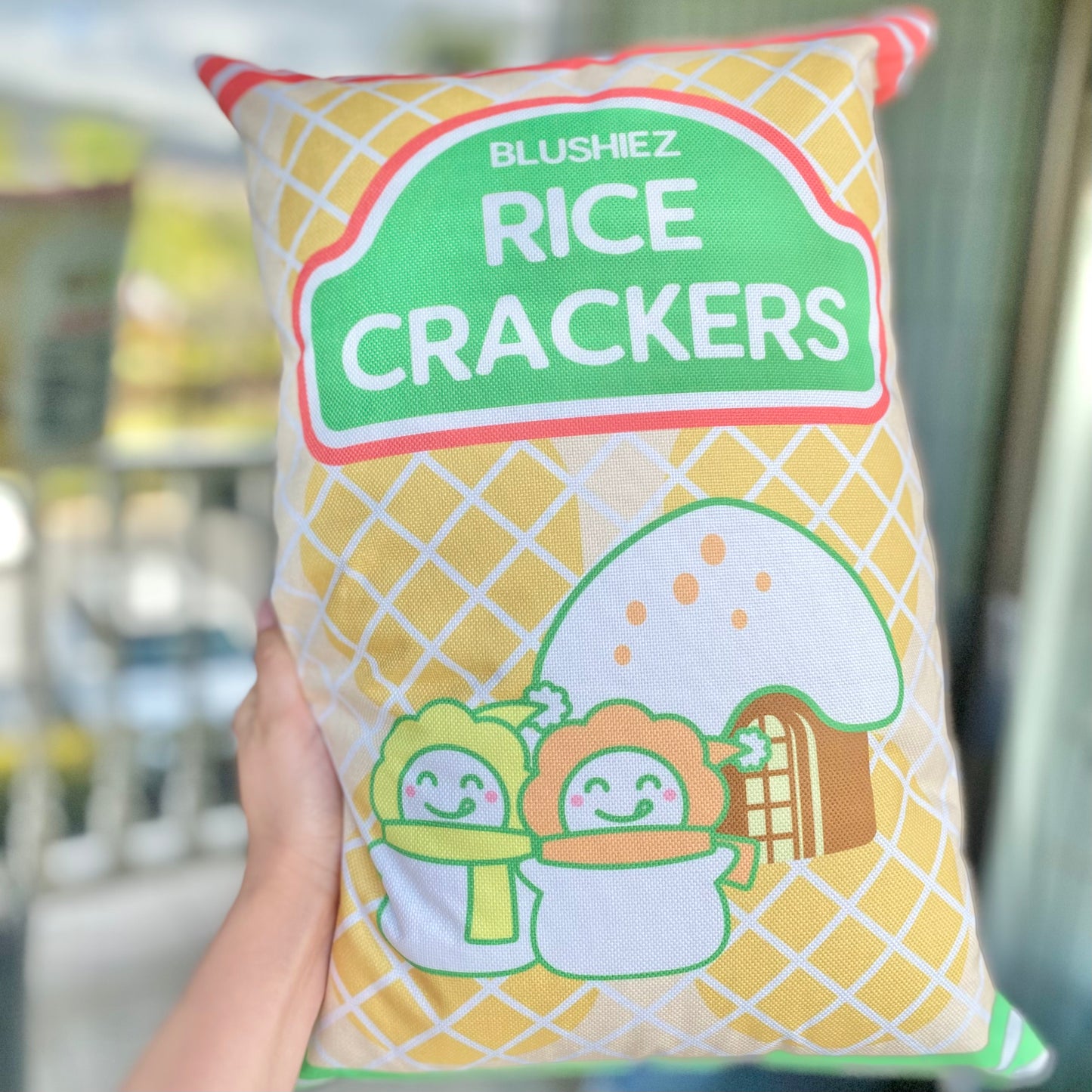 Pillow with a festive design resembling a snack-inspired pattern, held up by a woman's hand. The pillow features a light orange background with orange and green stripes, adding a playful touch. The woman's hand provides a sense of scale and demonstrates how the pillow can be held and displayed.
