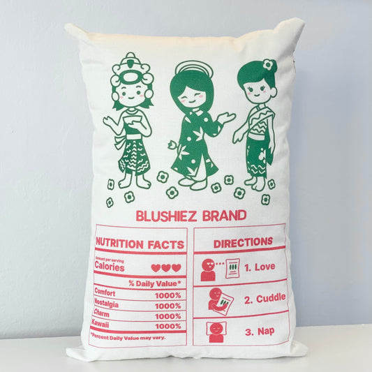 Back of the pillow featuring a playful design. The pillow resembles the packaging of Jasmine Rice, with a kawaii-style illustration of three girls in green dresses on a white background. The back side showcases a nutrition facts label with whimsical information, along with adorable directions encouraging love, cuddles, and napping on the pillow. These delightful details add a charming and inviting touch to the design.