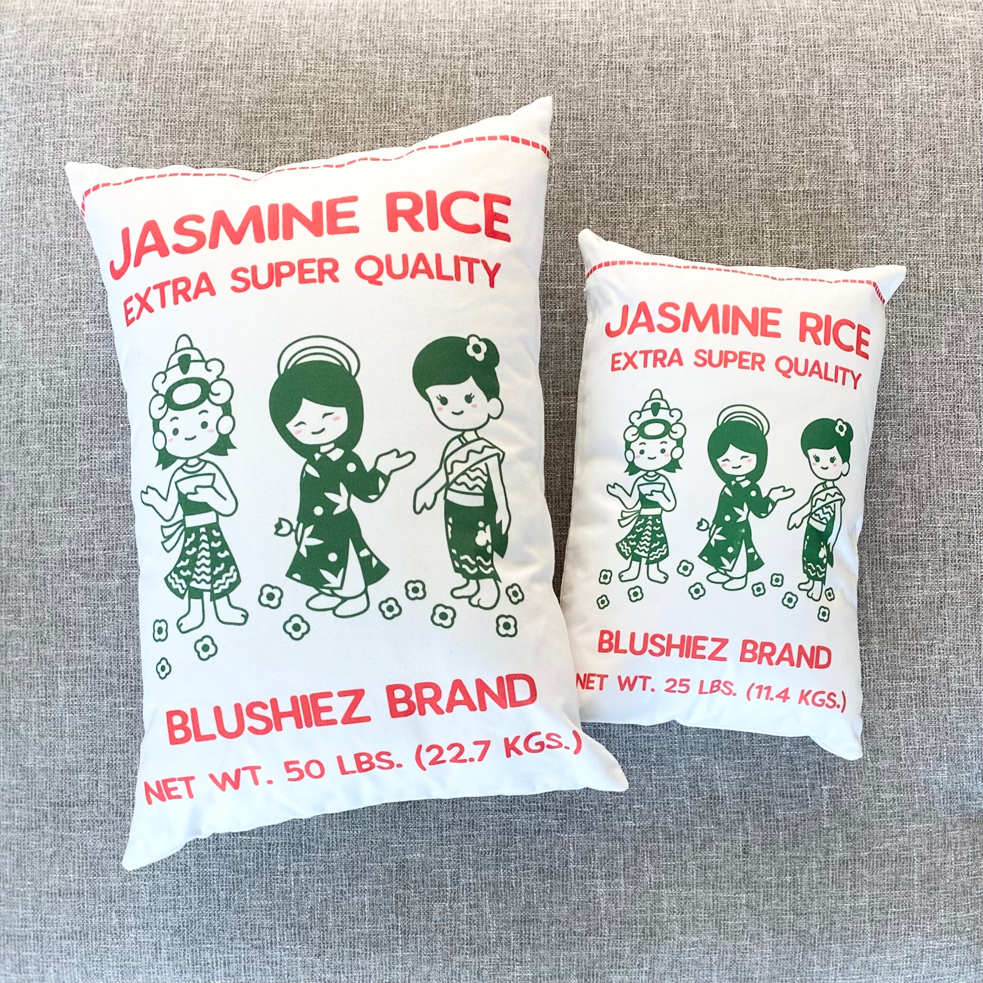 Comparison of large and small pillows inspired by Jasmine Rice packaging. The large size has a label reading '50 lbs' (not actual weight), while the small size has a label reading '25 lbs' (not actual weight). Both pillows feature a kawaii-style illustration of three girls in green dresses on a white background, resembling the vibrant imagery found on Jasmine Rice packaging.