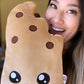 Woman holding a plush toy of a boba ice cream bar with a cute open-mouth smiling face. The plush toy is shaped like an ice cream bar with a bite taken out of the top right corner. The woman is smiling and appears to be taking a playful bite out of the corner.